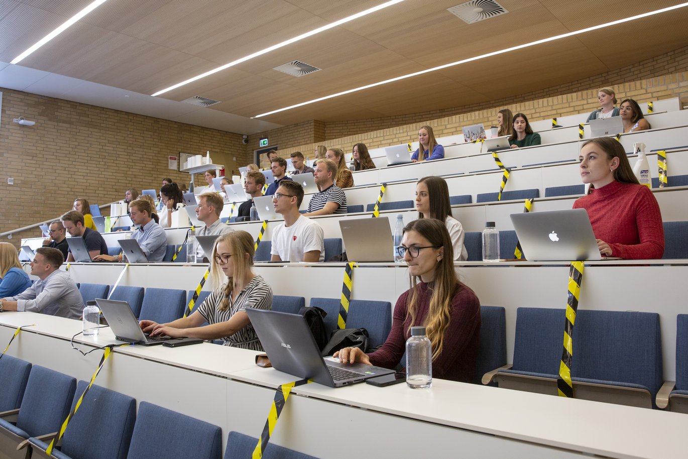 Studerende sidder i auditorium med corona-afspærringer