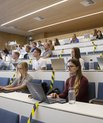 Studerende sidder i auditorium med corona-afspærringer